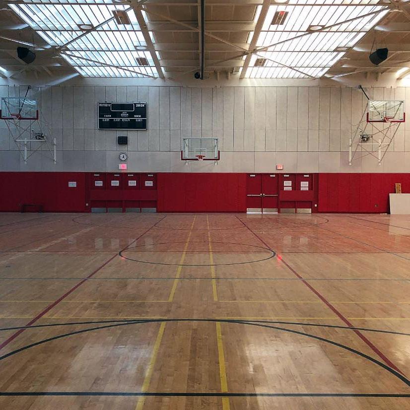 partial view of a gymnasium with a wood floor, protective padding on lower part of wall, 和天窗