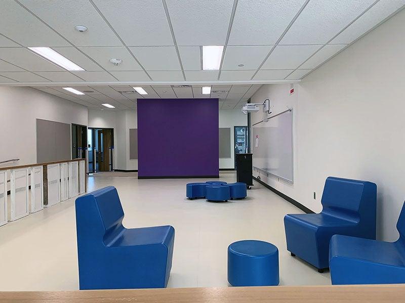 a group area has seating clusters, a learning wall, 还有一个教师站，用紫色的墙把它和走廊隔开