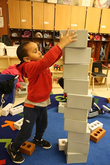 A young student stacks blocks in a classroom