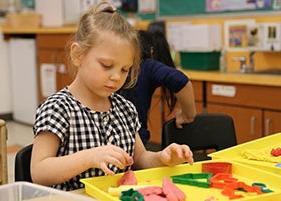 A young student plays with preschool toys in a classroom