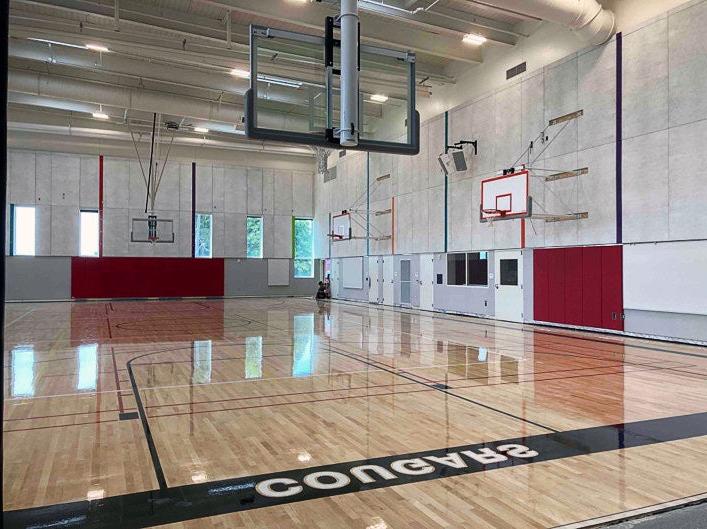an empty gymnasium with basketball hoops, floor striping, and the word Cougars on the floor