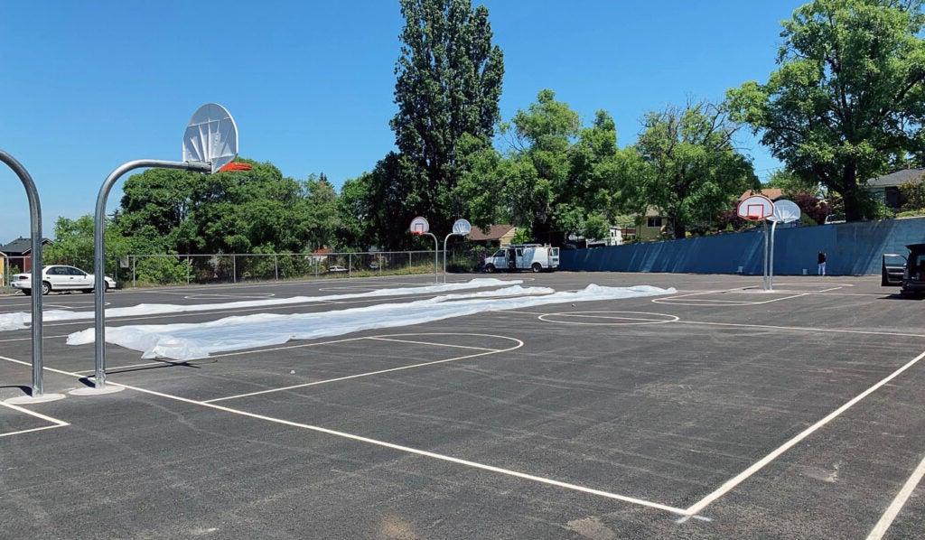 two basketball courts have striping and hoops
