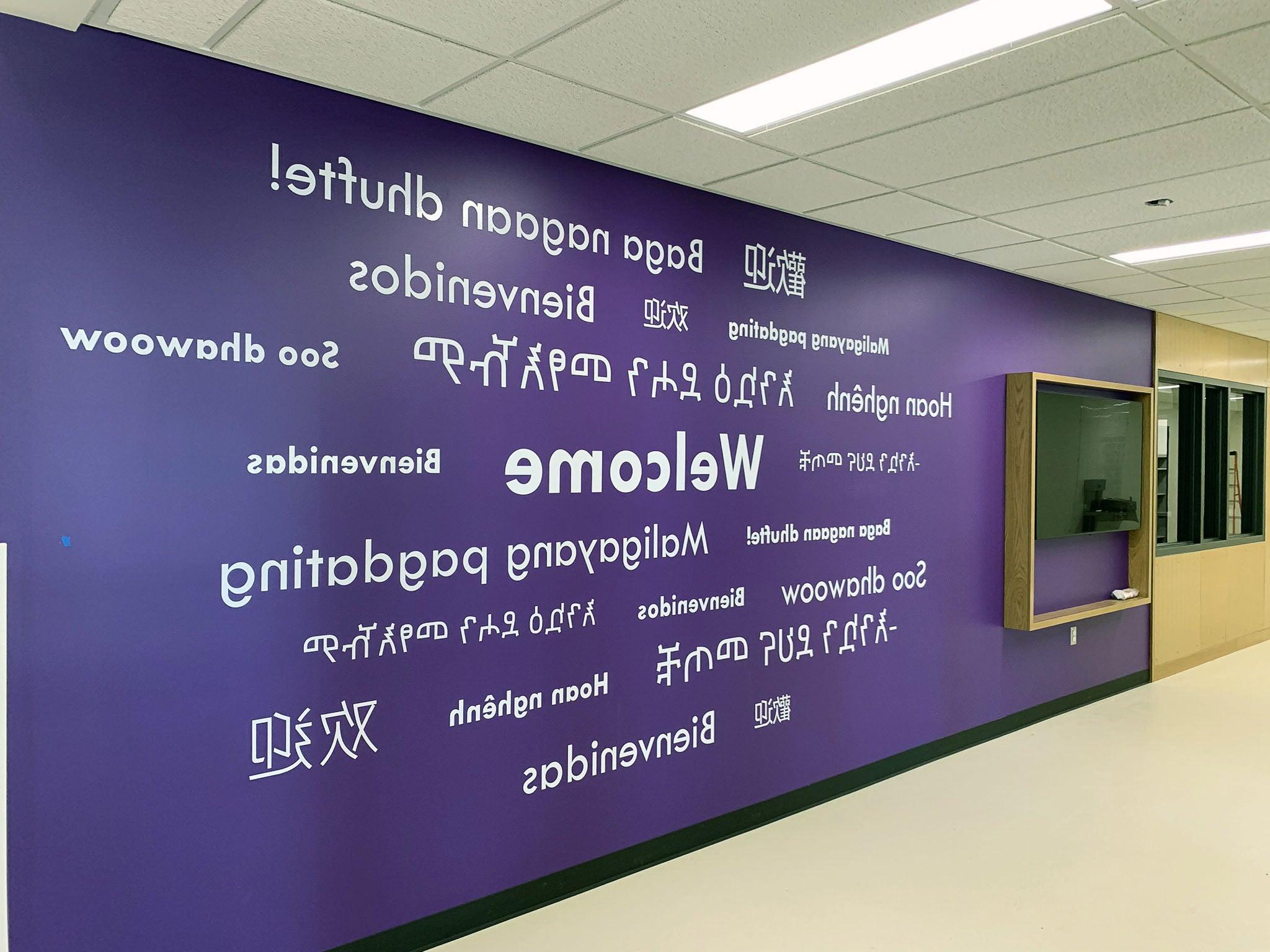 一面紫色的墙上用多种语言写着“欢迎”